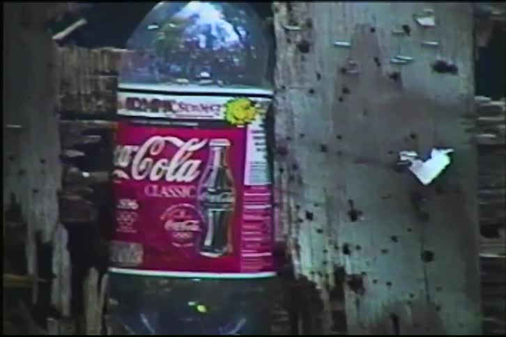 A vintage Coca-Cola bottle is shot during target practice, sending it flying backwards on impact