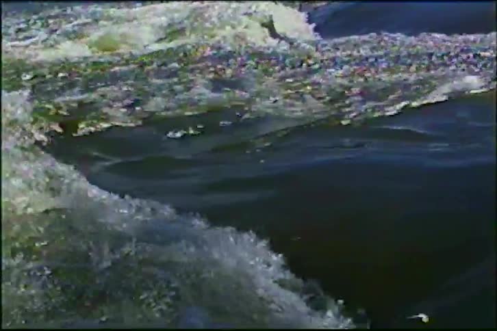 A close-up shot of powerful river rapids flowing over rocks, captured on vintage film