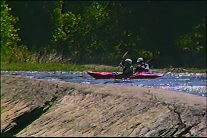 Vintage VHS footage shows a group of friends kayaking down a sunlit river
