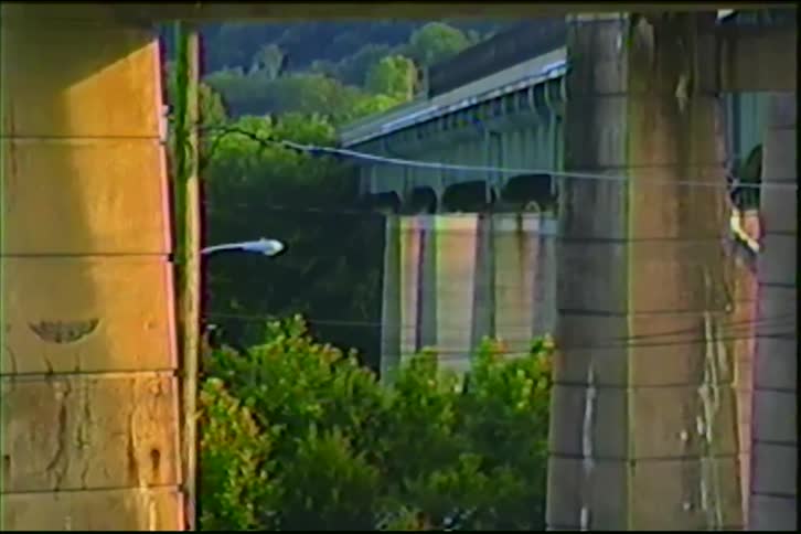 A MARC passenger train travels down the tracks as seen through concrete pillars in this vintage home video