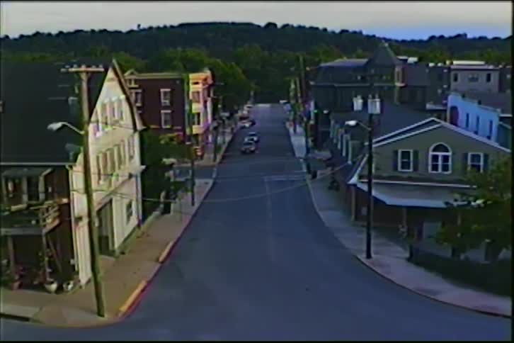 A slow pan across an empty, historic small town street at dusk with rolling hills in the background