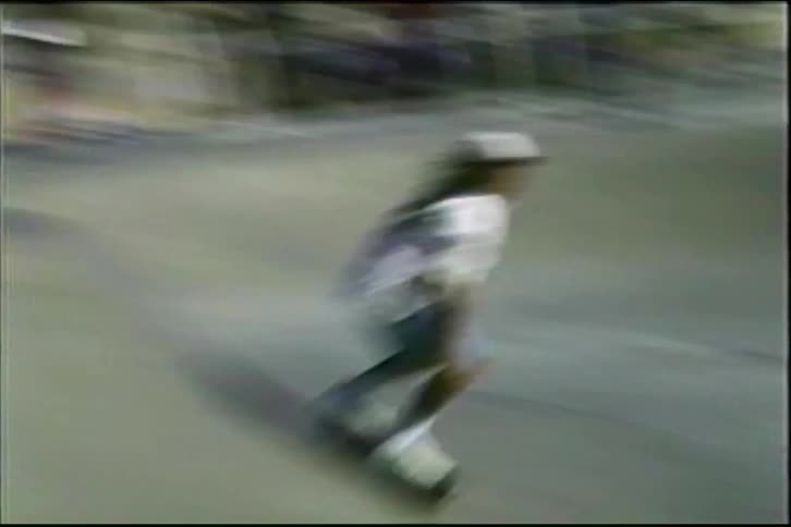 Vintage 90s footage of a skateboarder with long hair carving the walls of a concrete skate bowl