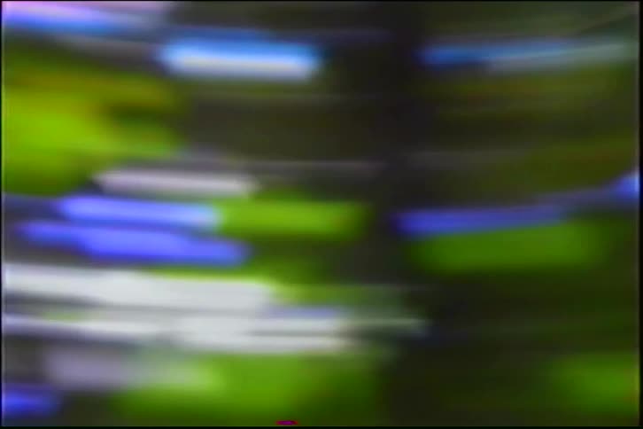 Chaotic and blurry horizontal light streaks of blue and green create a retro analog video effect