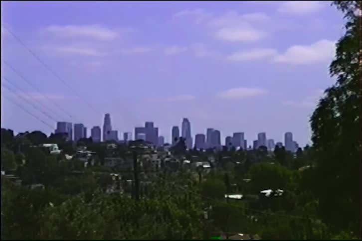 Vintage home movie footage from 1990 slowly zooms in on the downtown Los Angeles skyline from a residential neighborhood