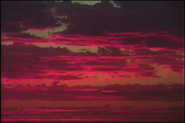 A dramatic sunset paints the clouds in vibrant shades of magenta and deep red