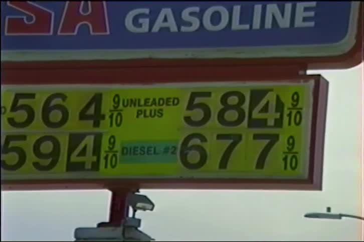 Vintage VHS footage slowly zooms in on a gas station sign displaying remarkably low prices from the past