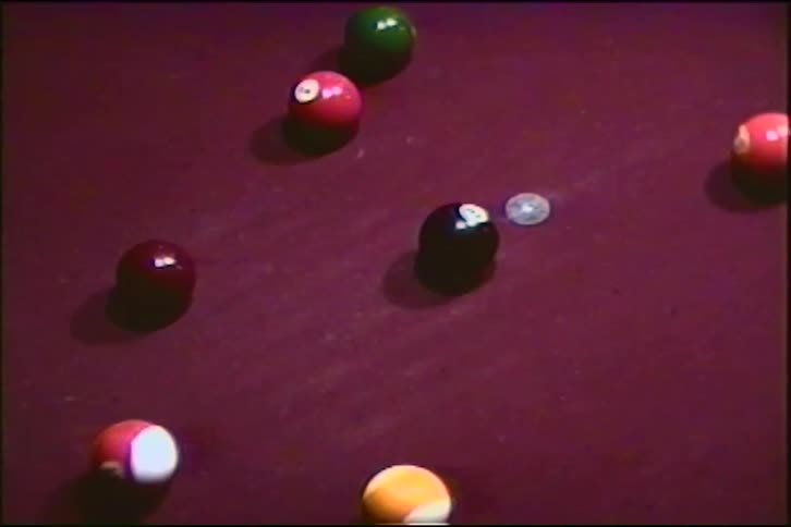 Vintage footage captures the explosive break shot in a game of pool on a purple felt table