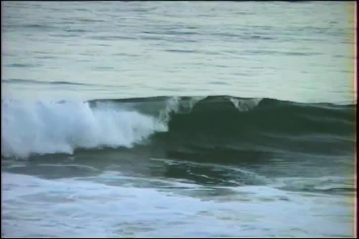 Close up slow motion footage of a powerful ocean wave cresting and crashing with white foam