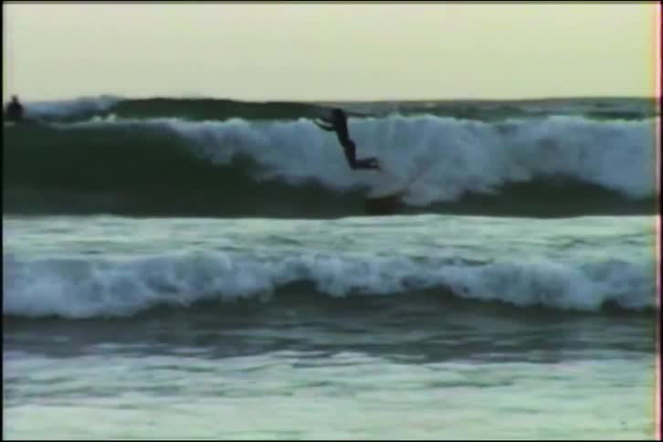 A surfer catches a wave in the ocean and dramatically wipes out in this vintage 1980s footage