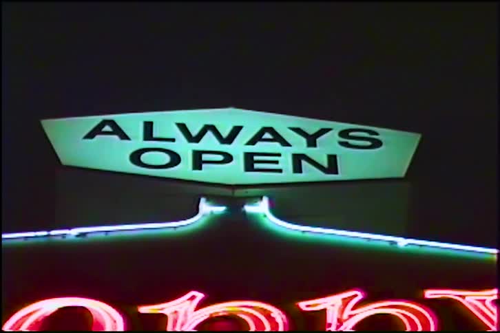 A retro VHS shot of a glowing green 'Always Open' neon sign at night