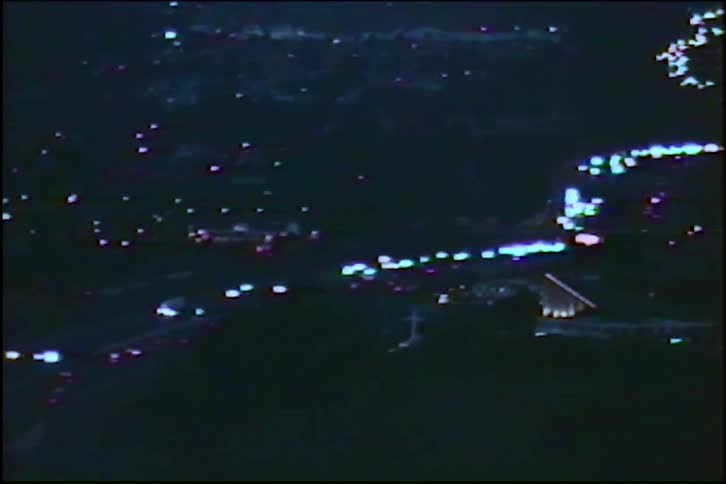 Vintage archival footage from 1983 shows a nighttime high-angle view of a city with traffic flowing on a highway