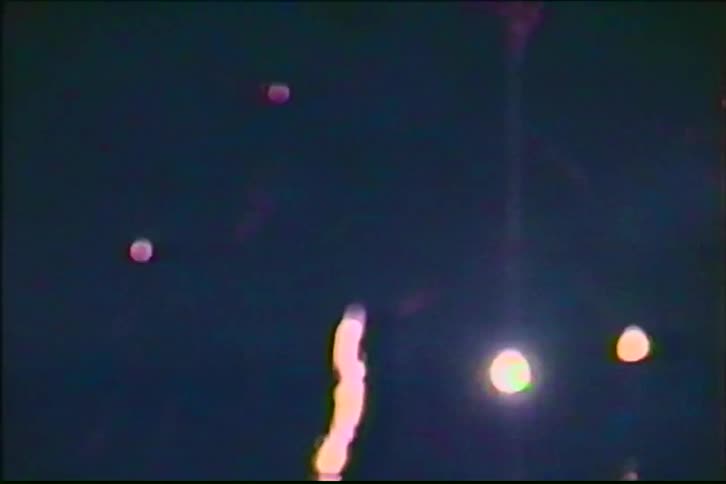 Vintage home video footage shows a backyard fireworks display lighting up the night sky