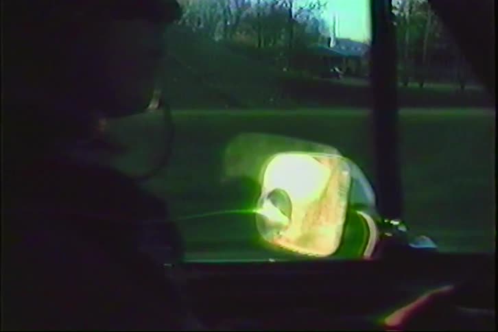 Vintage VHS footage shows the view from a car driving on a highway, passing under an overpass and then panning to the passenger