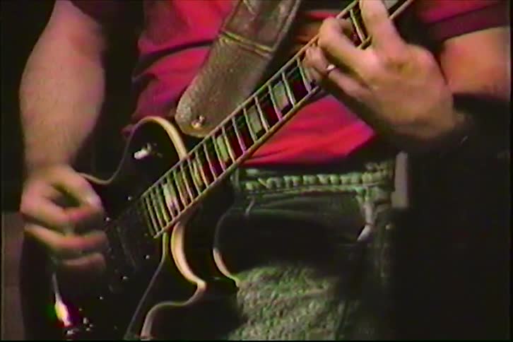 Vintage 1980s VHS footage shows a close-up of a musician's hands playing an electric guitar