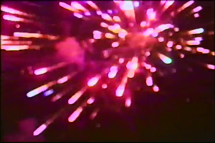 A vintage home video shows a close-up of a vibrant fireworks display lighting up the night sky