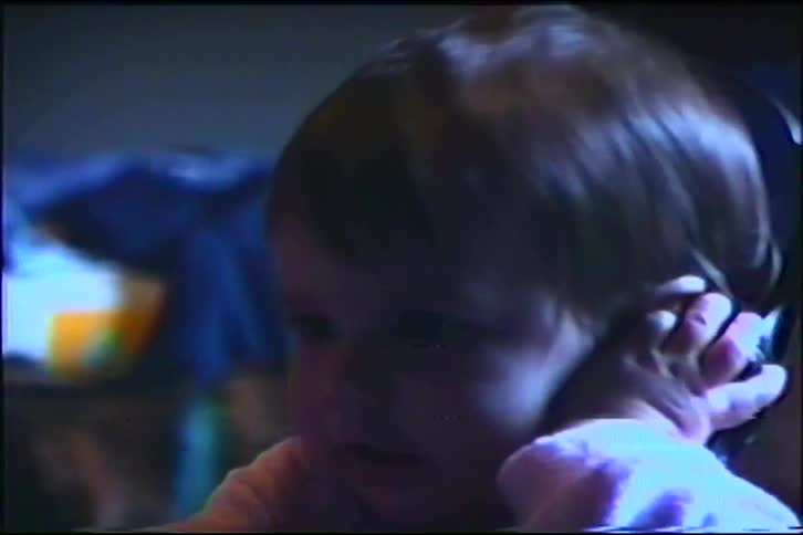 Vintage home movie captures a sweet toddler girl listening to music on old-school headphones in her bedroom