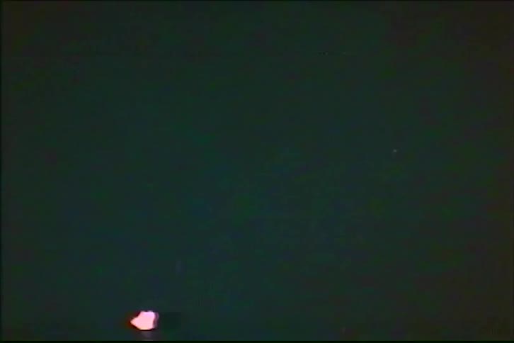 Vintage VHS footage captures a vibrant and colorful fireworks display exploding against the dark night sky