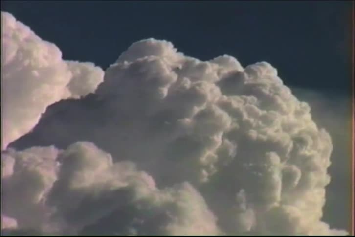 A close-up time-lapse of majestic, white cumulus clouds slowly billowing against a deep blue sky