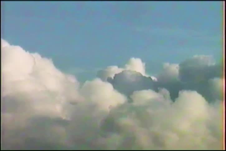 A vintage VHS shot looking down at a vast sea of fluffy white clouds floating in the blue sky