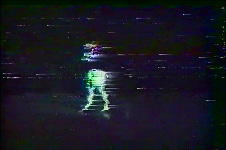 Distorted VHS footage shows the glowing, glitchy silhouette of a person dancing against a dark background