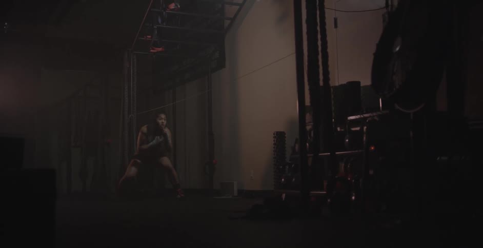 A woman practices sparring in a dim room