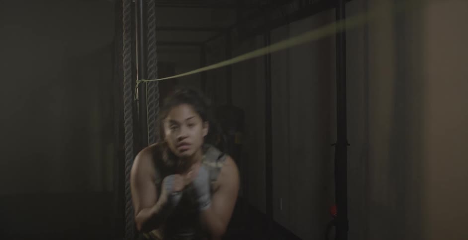 A female fighter is training using a rope line in a gym