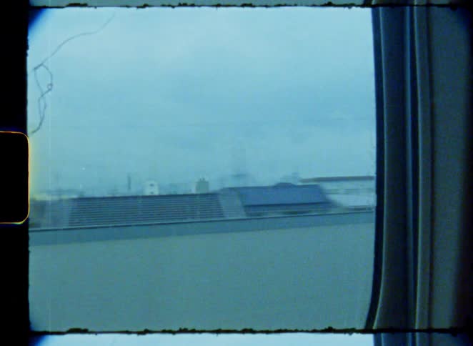 Vintage 8mm footage of the Japanese landscape passing by as seen from a fast-moving train window on a gloomy day