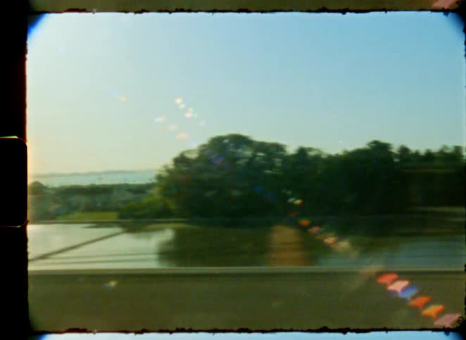 A dreamy, vintage 8mm film view of the rural landscape with mountains in the distance from a moving train