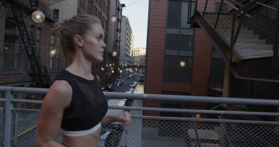 A woman is jogging over a bridge in the city