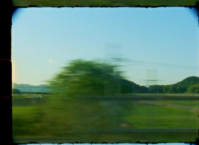 Nostalgic 8mm film captures the serene view of the Japanese countryside passing by from a train window