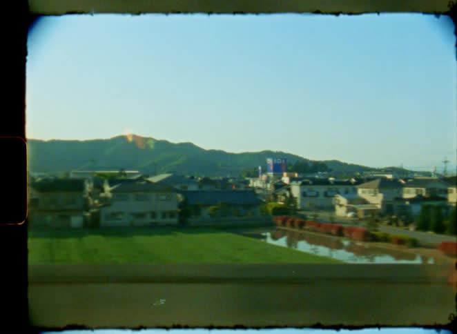Vintage film footage captures a peaceful journey through the Japanese countryside, passing rice paddies and green hills from a train window