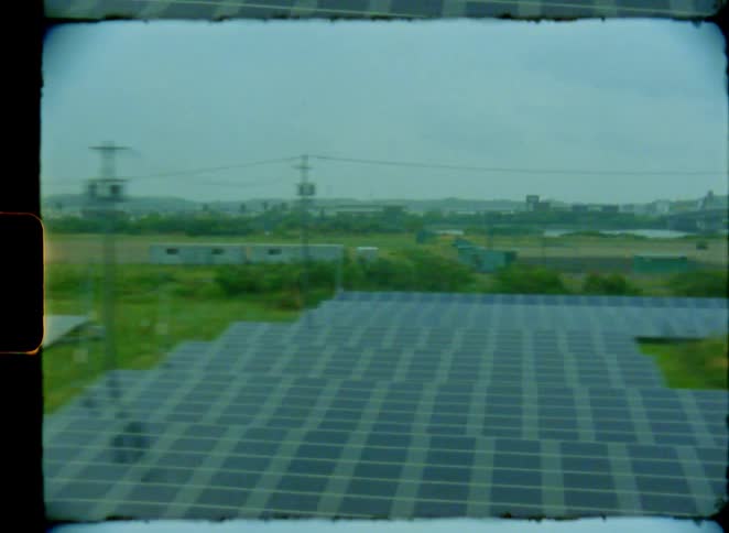 Dreamy vintage 8mm film captures the view of a solar panel farm and industrial landscape from a moving train window