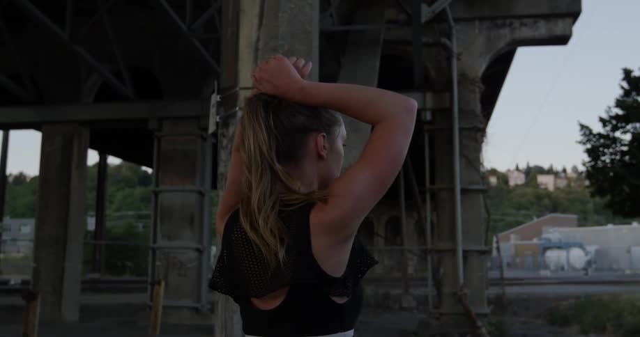 Woman resting while standing with her hands on her head next to an underpass