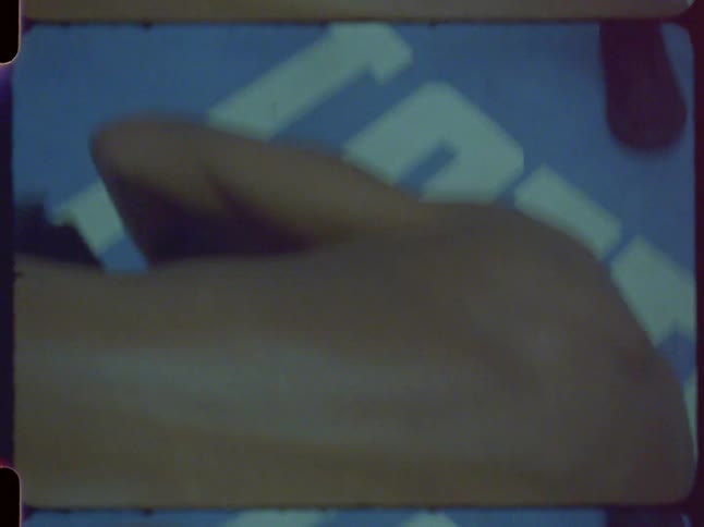Authentic vintage film captures a boxer's training session with close-up shots of their muscular back and gloves in a dimly lit ring