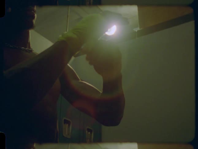Low-angle shot of a boxer wrapping his hands with yellow tape in a dimly lit locker room, captured on 8mm film