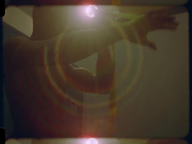 Muscular shirtless boxer carefully wraps his hands with yellow tape in a dark locker room, illuminated by a single light creating a dramatic lens flare