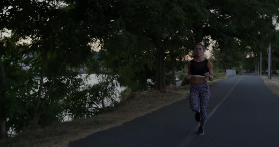 A woman is jogging on the road by the water