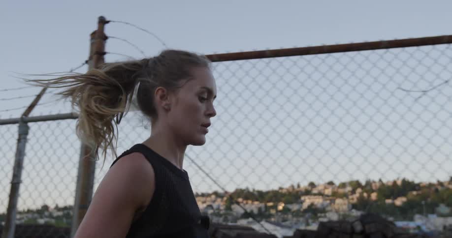 Woman runs next to a chain link barbed wire fence
