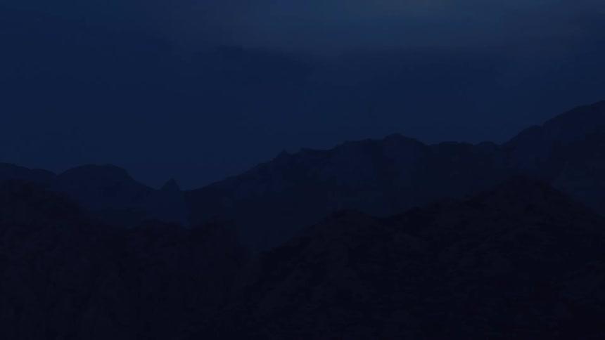 The silhouette of a mountain range is barely visible against a deep blue night sky