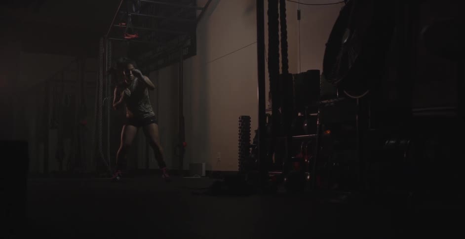 Woman shadowboxing and training while bobbing back and forth beneath a rope