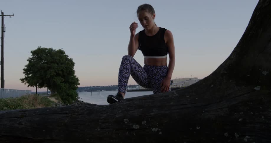 A woman walks over to a fallen log