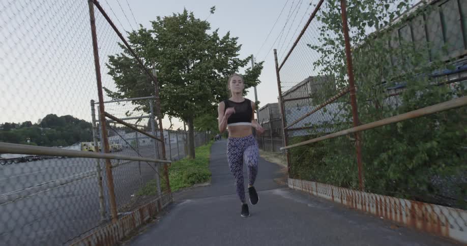 A woman jogs in a city at sunset