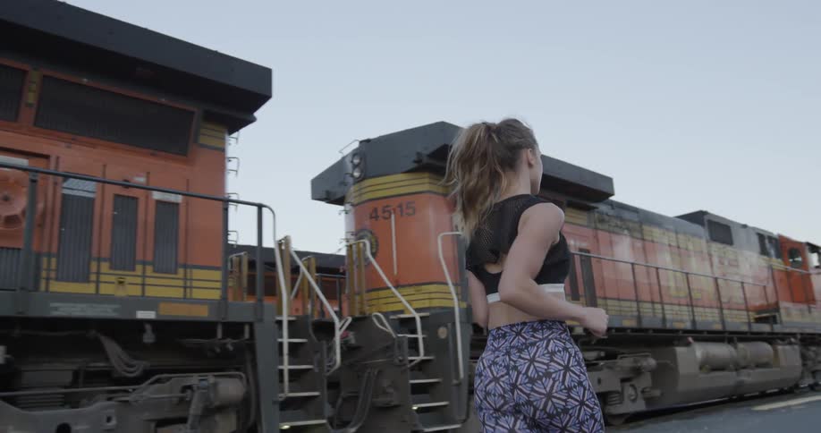 A female jogger is running past train cars
