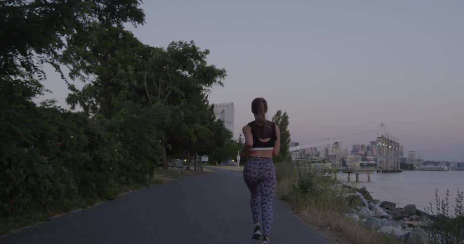 Woman runs on a road alongside water