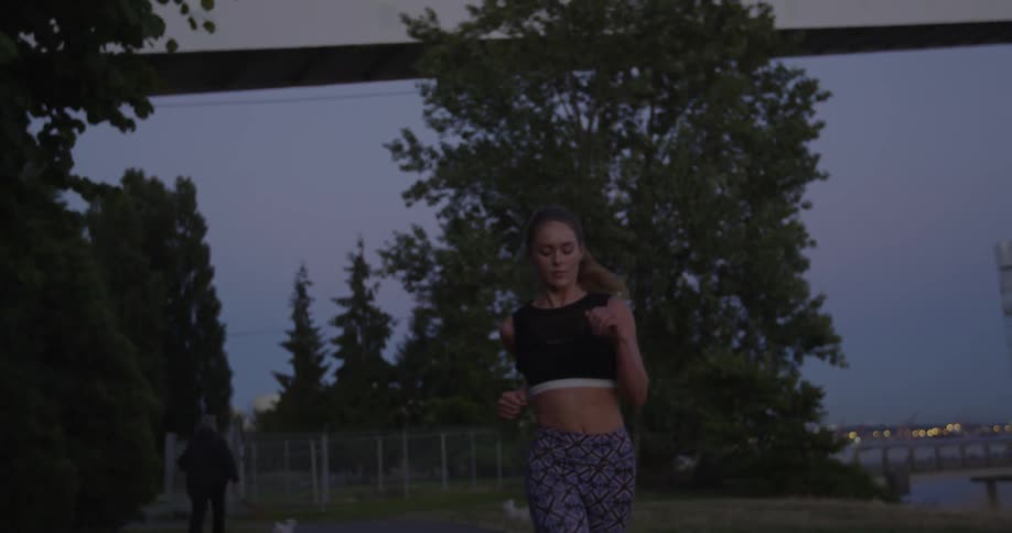 A woman jogs in a park at dusk