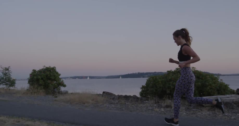 Woman jogging next to a lake in slow motion