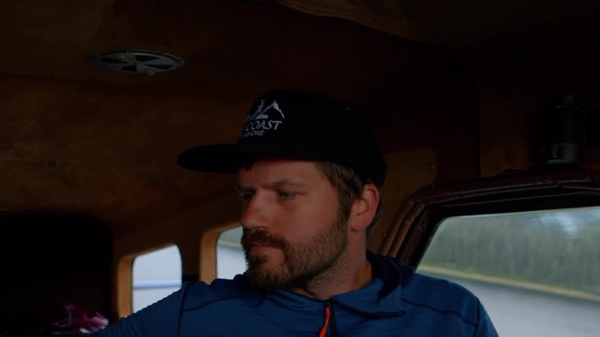 Close-up of a focused fishing guide wearing a cap inside the cabin of a boat as it moves across the water