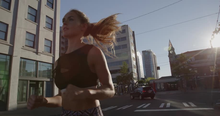 A woman is jogging in the street on a sunny day