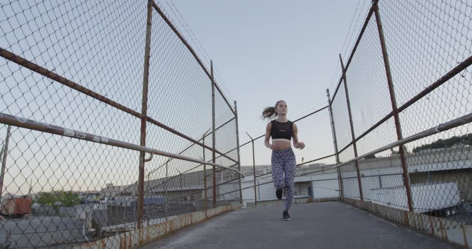 A woman jogs over a pedestrian overpass