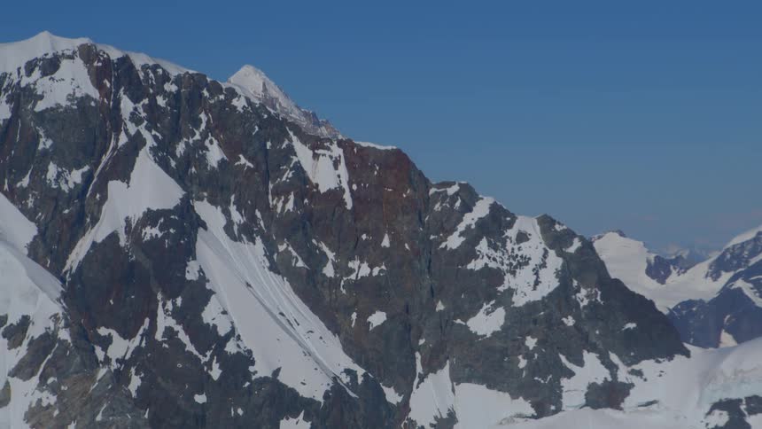 An epic aerial view slowly pans across the vast and rugged snow-covered peaks of a remote mountain range